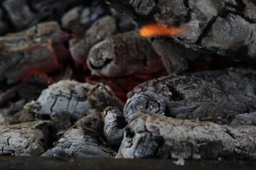 Smoldered logs burned in vivid fire close up. Atmospheric background with flame of campfire. Unimaginable detailed image of bonfire from inside with copy space. Whirlwind of smoke and glowing embers.