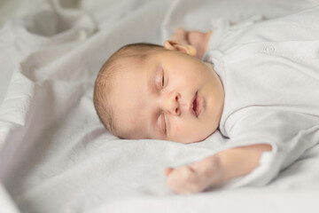 Sleeping newborn baby in a wrap on white blanket. Beautiful portrait of little child girl, one week old.