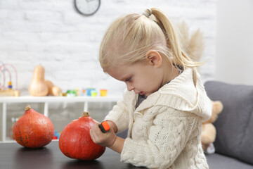 Fototapeta premium Cute little girl playing with Halloween decorations. Autumn DIY craft at home.