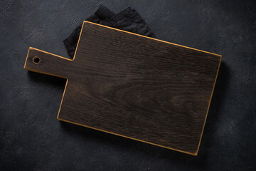 Black wooden cutting board on black table.