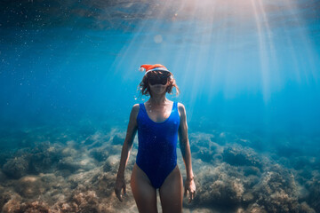Happy freediver woman with Christmas cap posing underwater in blue sea. Christmas holidays concept