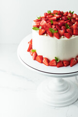 White buttercream cake decorated with strawberries and mint leaves