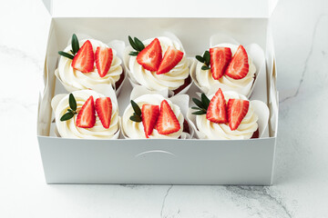 Chocolate cupcakes with white cream top decorated with strawberries.