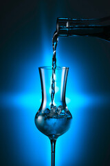 Steamed glass with strong alcoholic drink on a blue background.