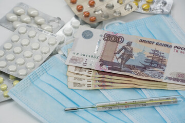 A thermometer, a pill, a medical mask and money in Rubles are on the table. Increase in prices for medicines in Russia in Rubles. Russia is on quarantine because of the epidemic of the coronavirus