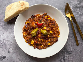 Chili con carne with minced beef, tomatoes, chili peppers, beans, corn, onions, garlic and bell pepper. Served with flat bread.