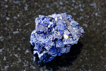 macro photography of sample of natural mineral from geological collection - raw Azurite mineral crystals from Jezkazgan, Kazakhstan on black granite background