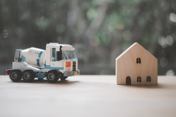 Concrete mixer truck plastic toy and miniature wood home.