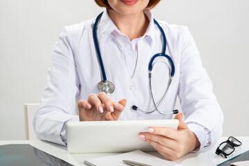 Close up female doctor hands using tablet computer