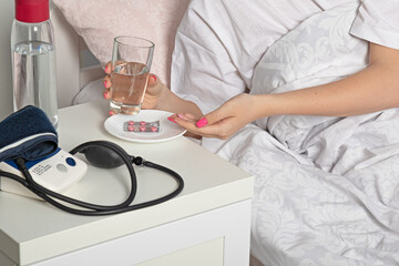 sick girl  holds pills and  glass of water in her hands.Health care concept.Self-medication of the virus
