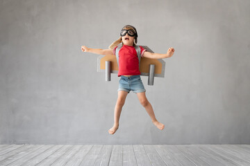 Fototapeta na wymiar Child with jetpack jumping against grey concrete background