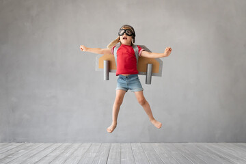 Child with jetpack jumping against grey concrete background © Igor Yaruta