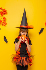 Little girl wearing witch costume drinking tea for Halloween