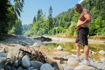 Young man is carving the wood for a barbecue - Adventure outdoor