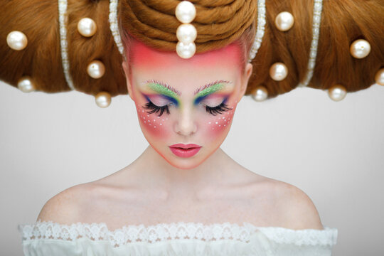 Girl with a creative makeup and hairstyle with huge pearls. The concept of hairdressing art., over light background.