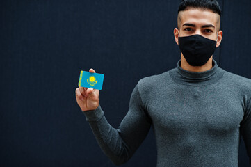 Middle eastern man in gray turtleneck and black face protect mask show Kazakhstan flag isolated background.