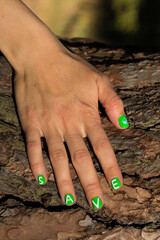 Hand with green manicure on the trunk of the tree. Save the planet concept
