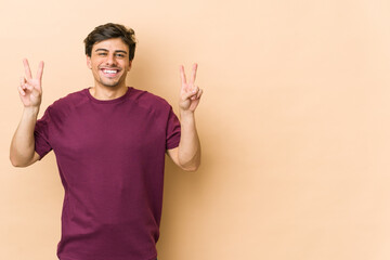 Fototapeta premium Young cool man showing victory sign and smiling broadly.