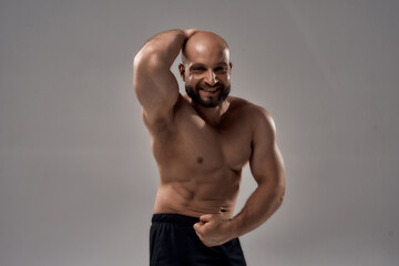 Muscular body. Strong athletic caucasian man bodybuilder showing his muscles, chest, biceps, abs and looking at camera while posing shirtless isolated over grey background