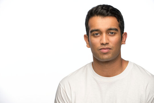 Portrait of young Indian man looking at camera with straight face