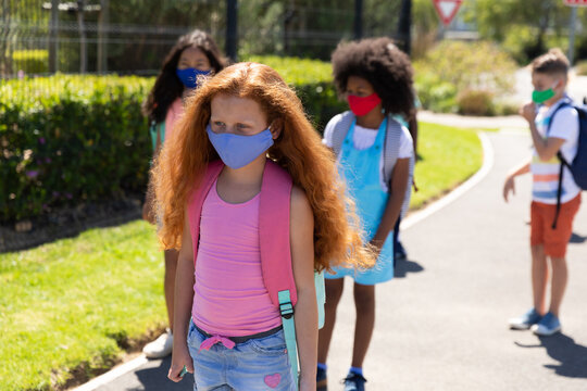 Group of kids wearing face masks walking on the road