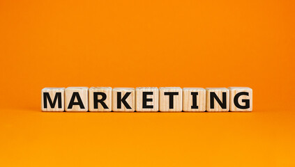 Concept word 'marketing' on wooden cubes on a beautiful orange background. Business concept, copy space.