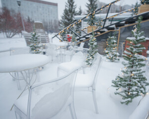 Tables and chairs in a cafe covered with snow outdoors.