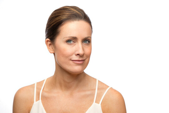 Portrait of middle aged white woman with brown hair pulled back, looking at camera with a slight smile 