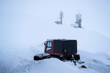 Snow grooming machine, snow manipulation for recreational uses and in the background is the weather...