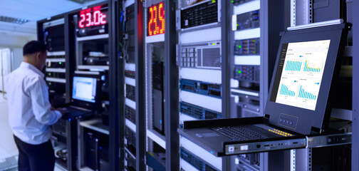 blur System administrator in a technology data center room and selective focus at monitor show graph information of network traffic and status of device