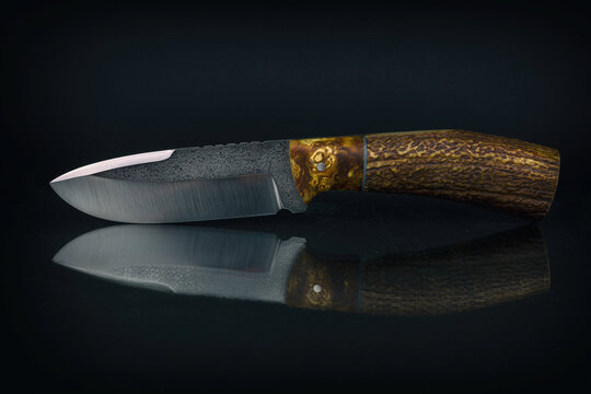 handmade custom fixed blade knife with antler handle. Isolated on black background.