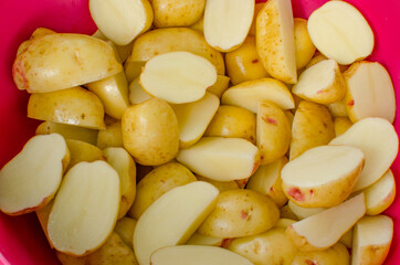 Raw chopped potatoes in a plastic bowl.