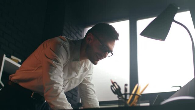 Low angle shot of successful smiling businessman, watching reading on laptop, feeling happy and satisfied with good results, celebrating victory at stock market, glad to receive promotion