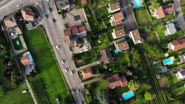Panning top down aerial shot, small Wintzenheim town at Alsace, France. Modern cottage buildings and mansions, car traffic on Route de Rouffach, empty Route de Colmar