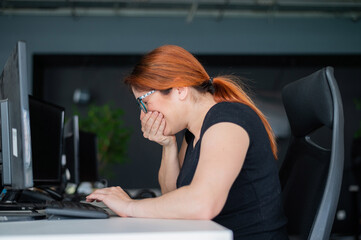 A woman is sick and sneezes at the desk in the office