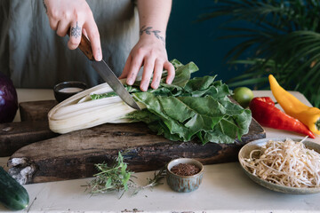 Young woman cutting pak choi on chopping board