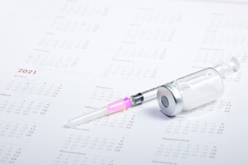 Medical concept. In the calendar, syringe with container of epidemic vaccine.