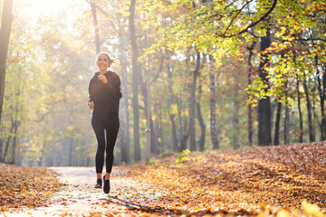 Young woman jogging in autumn forest
