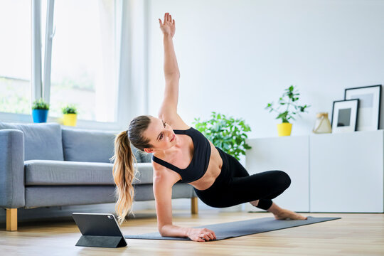 Woman learning side plank exercise on internet through digital tablet