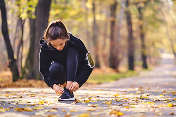 Young woman tying her running shoe