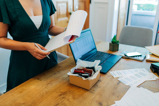 Midsection of female professional standing with clipboard at desk in office