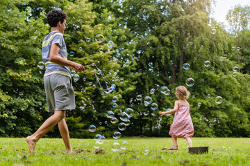 Brother and sister playing with bubbles in park