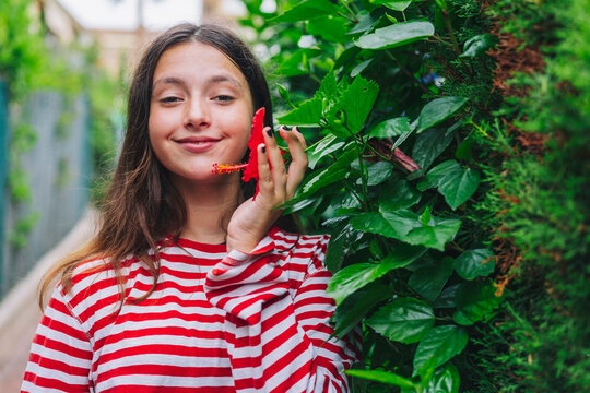 Smiling girl holding hibiscus flower while standing in backyard