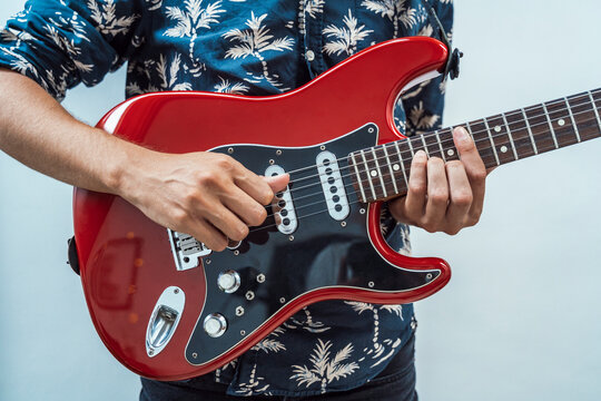 Musician playing guitar against wall