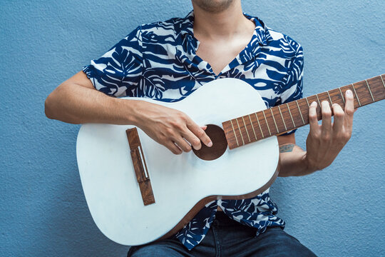 Musician playing guitar against blue wall