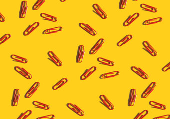 red paper clips on a bright yellow background. School supplies top view. Colorful background