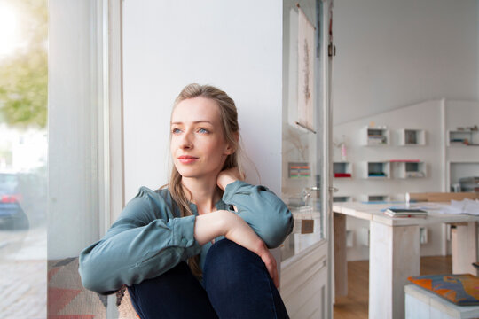 Relaxed woman having a break in home office looking out of window