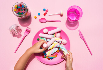 Hands of baby girl picking up sweets from plastic plate
