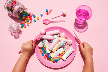 Hands of baby girl preparing to eat plate filled with various sweets