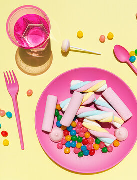 Studio shot of glass of water and plastic plate filled with various sweets